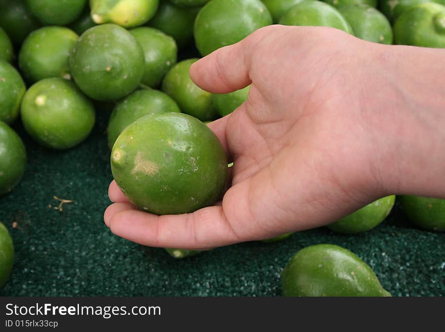 Hand holding a lime at an outdoor market. Hand holding a lime at an outdoor market.