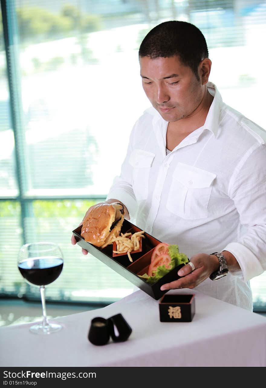 Asian Male waiter at table with hamburger