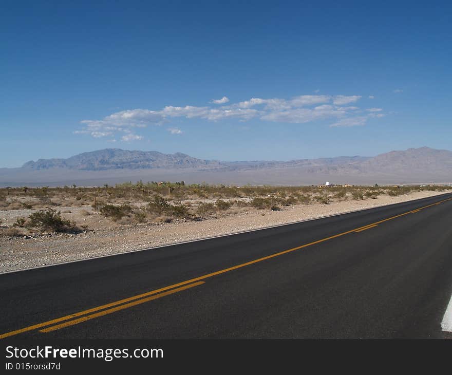 The yellow, no crossing line on raod through desert, hills in background. The yellow, no crossing line on raod through desert, hills in background.