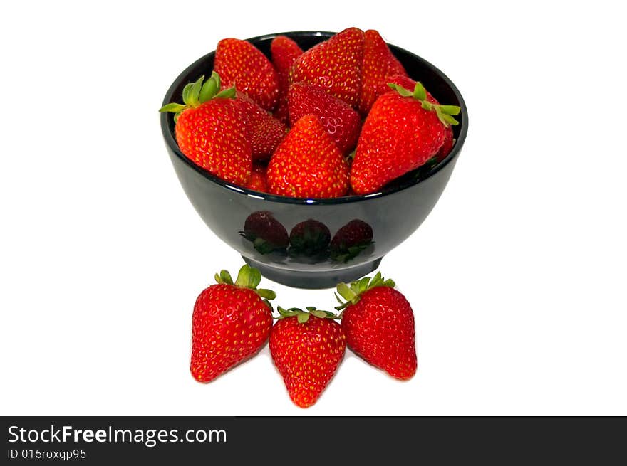 A bowl of strawberries with some in front