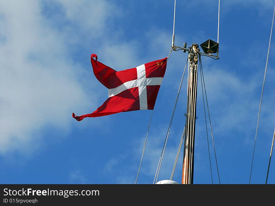 Red flad with white cross on Danish sailboat mast and blue sky. Red flad with white cross on Danish sailboat mast and blue sky.