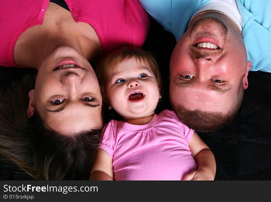 A mother, father and daughter looking up at the camera. A mother, father and daughter looking up at the camera