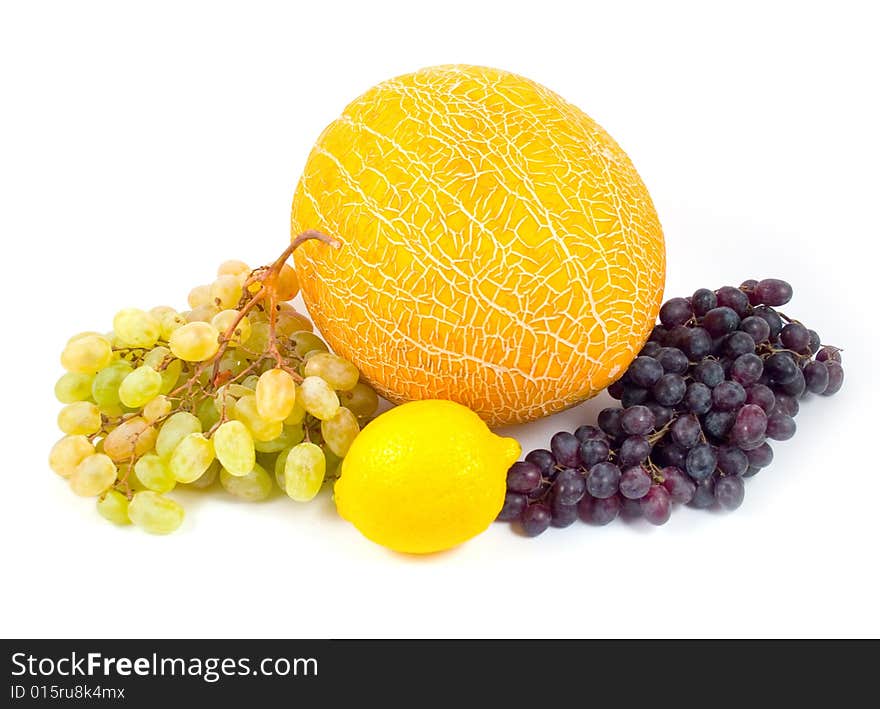 Ripe yellow melon and lemon with green and black grapes on white background