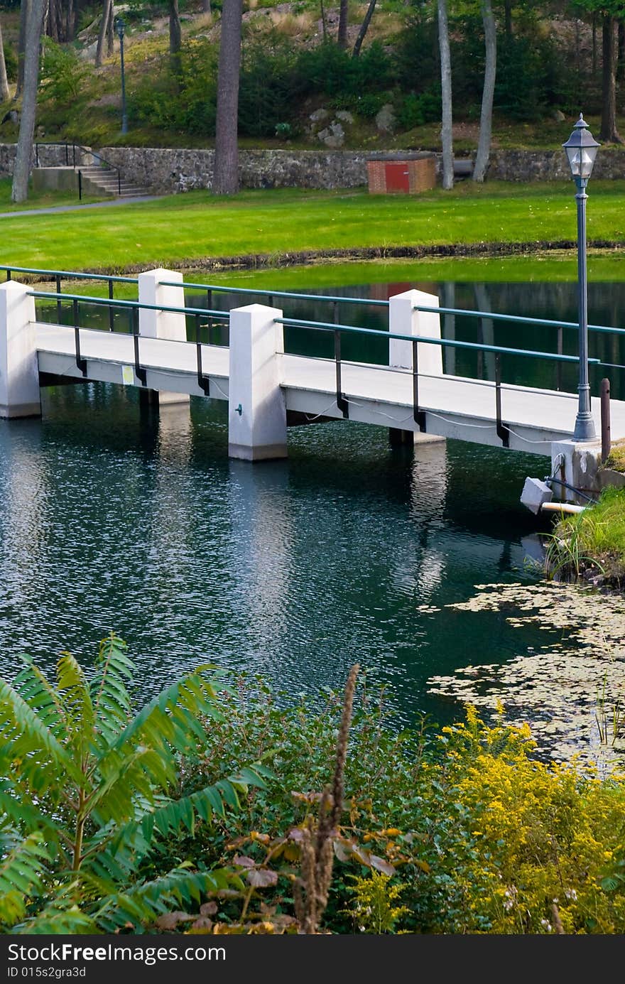 Foot bridge reflected in pond  in  Beverly, Massachusetts. Early fall when the trees are beginning to change colors.