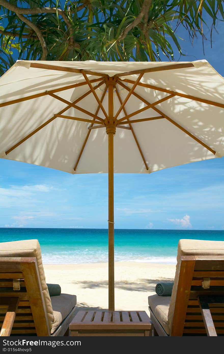 View of two chairs and white umbrella on the beach. View of two chairs and white umbrella on the beach.