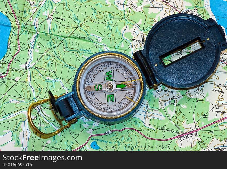 The compass lays on a green map. The compass lays on a green map