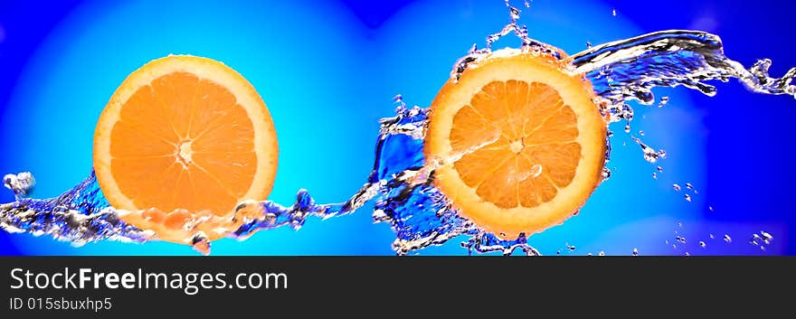 Close up view of two sliced orange pieces getting splashed with water. Close up view of two sliced orange pieces getting splashed with water