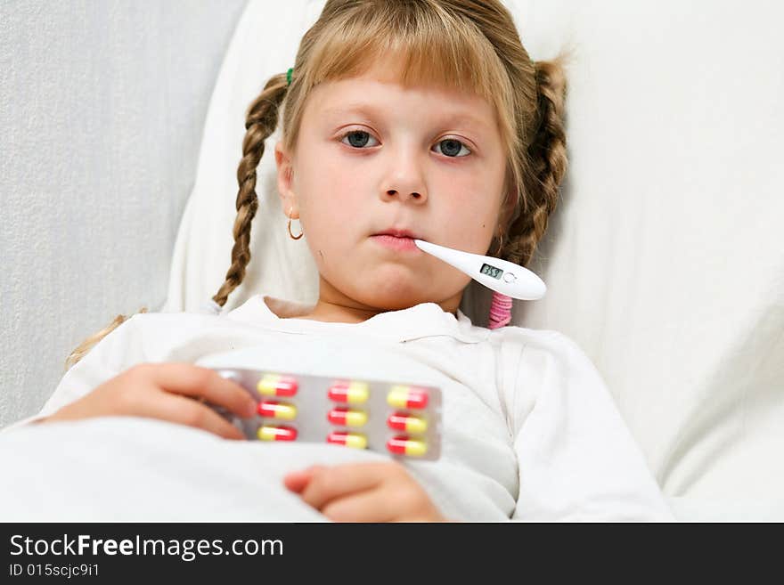 Young girl in bed with thermometer in mouth