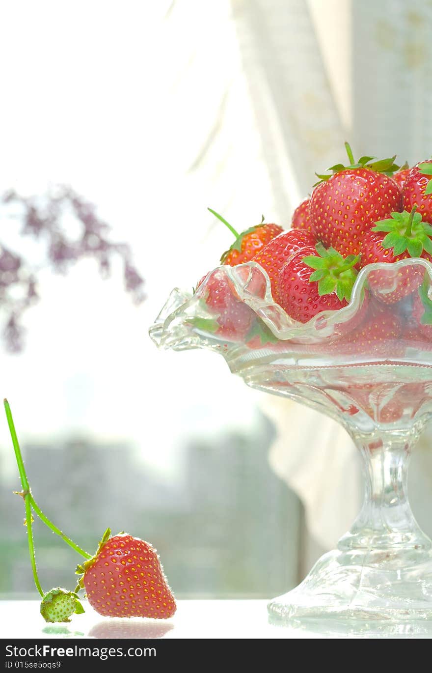 High key photo of fruit dish filled with nice red strawberries