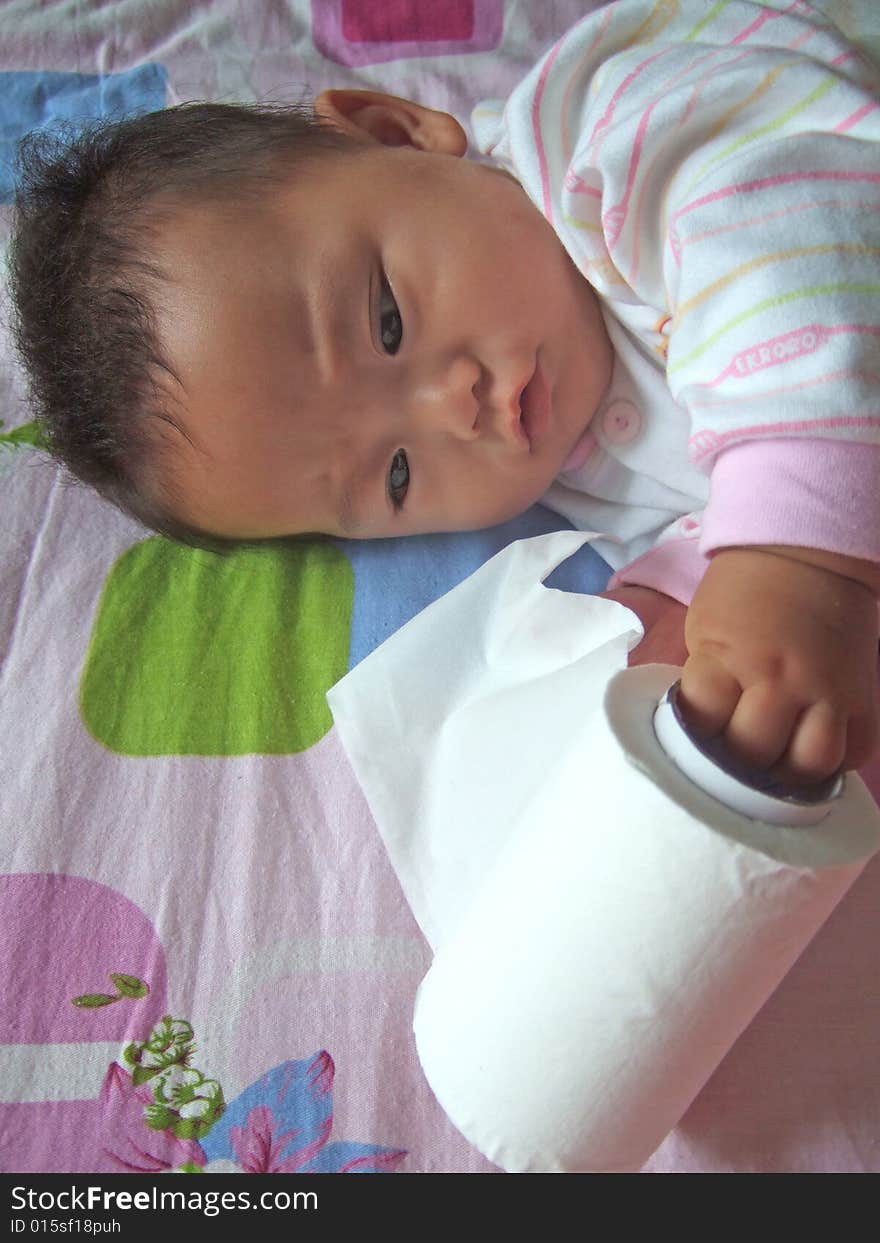 Cute baby is playing paper on a bed. Cute baby is playing paper on a bed