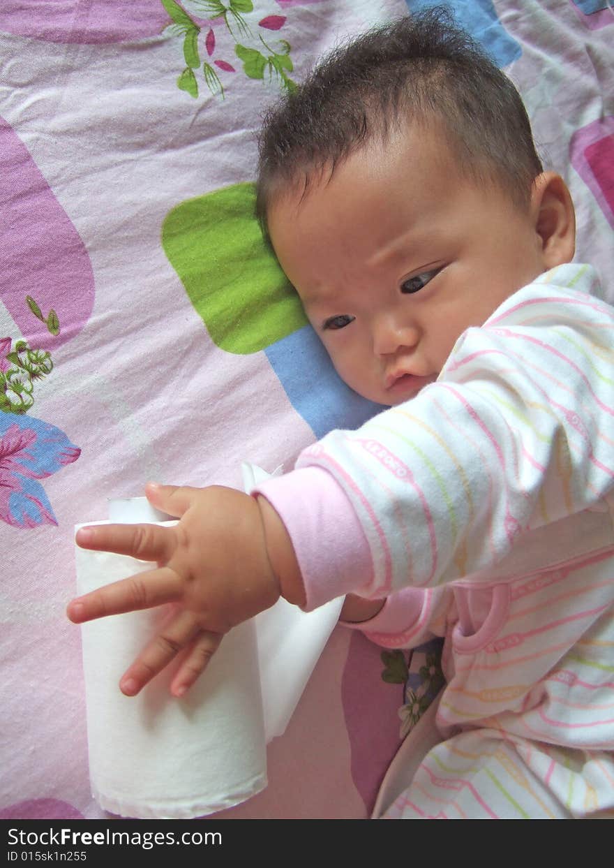 Cute baby is playing paper on a bed. Cute baby is playing paper on a bed