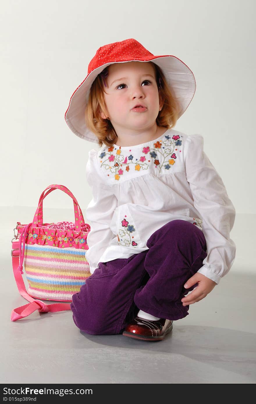 Blond Toddler Plays With Red Hat