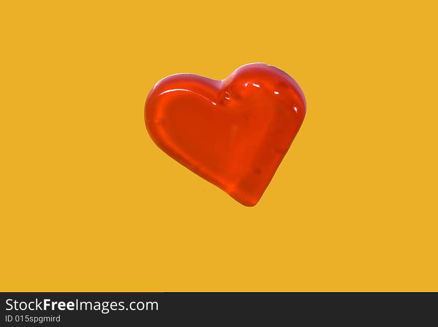 Red candy heart isolated on yellow background