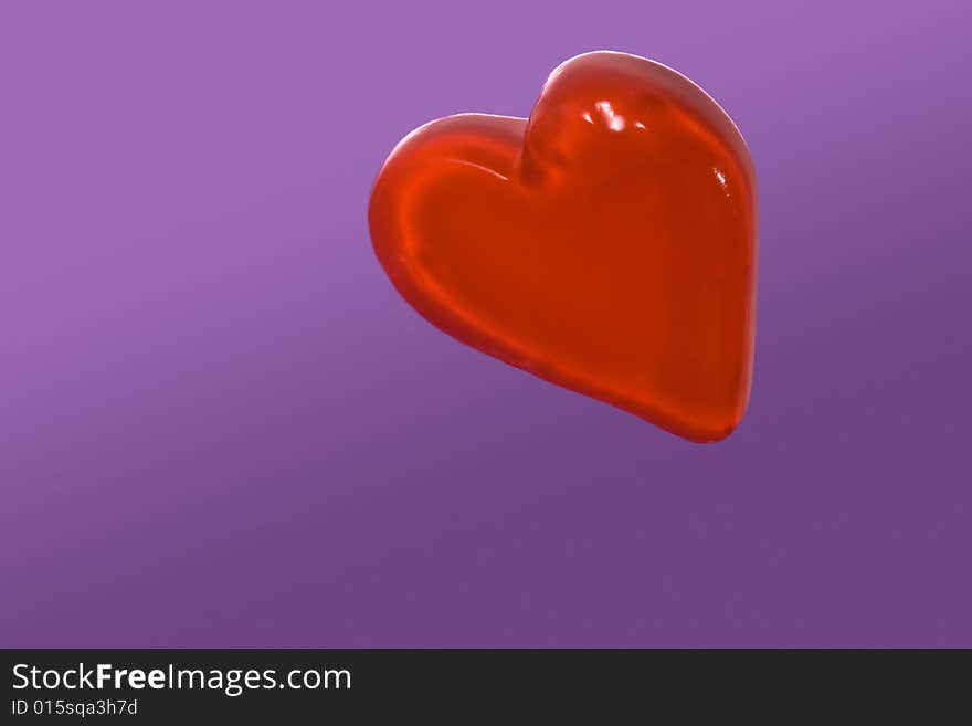 Red candy heart isolated on purple background