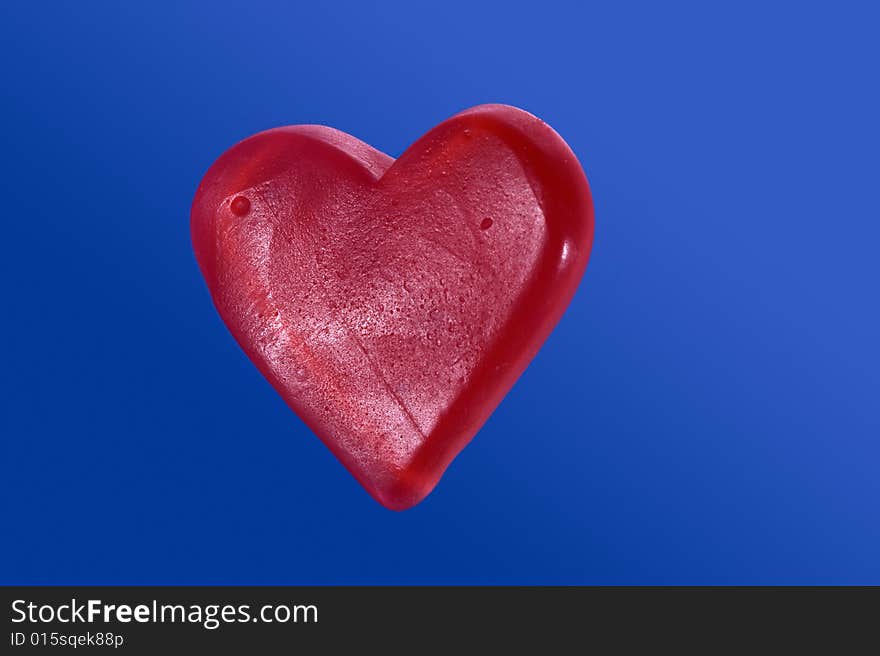 Red candy heart isolated on blue background