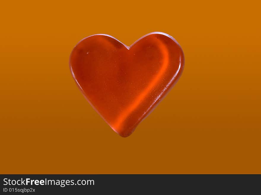 Red candy heart isolated on orange background