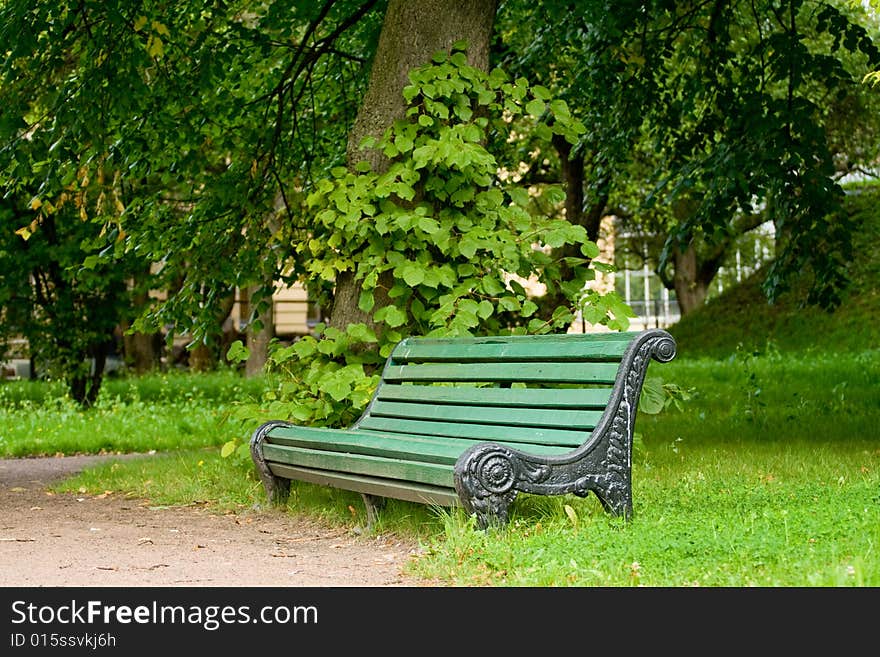 Empty old wooden green bench in the urban garden. Empty old wooden green bench in the urban garden