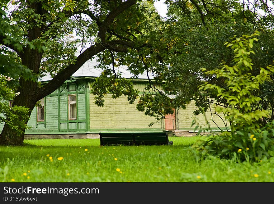 Empty green bench in the urban garden and old wooden house. Empty green bench in the urban garden and old wooden house.