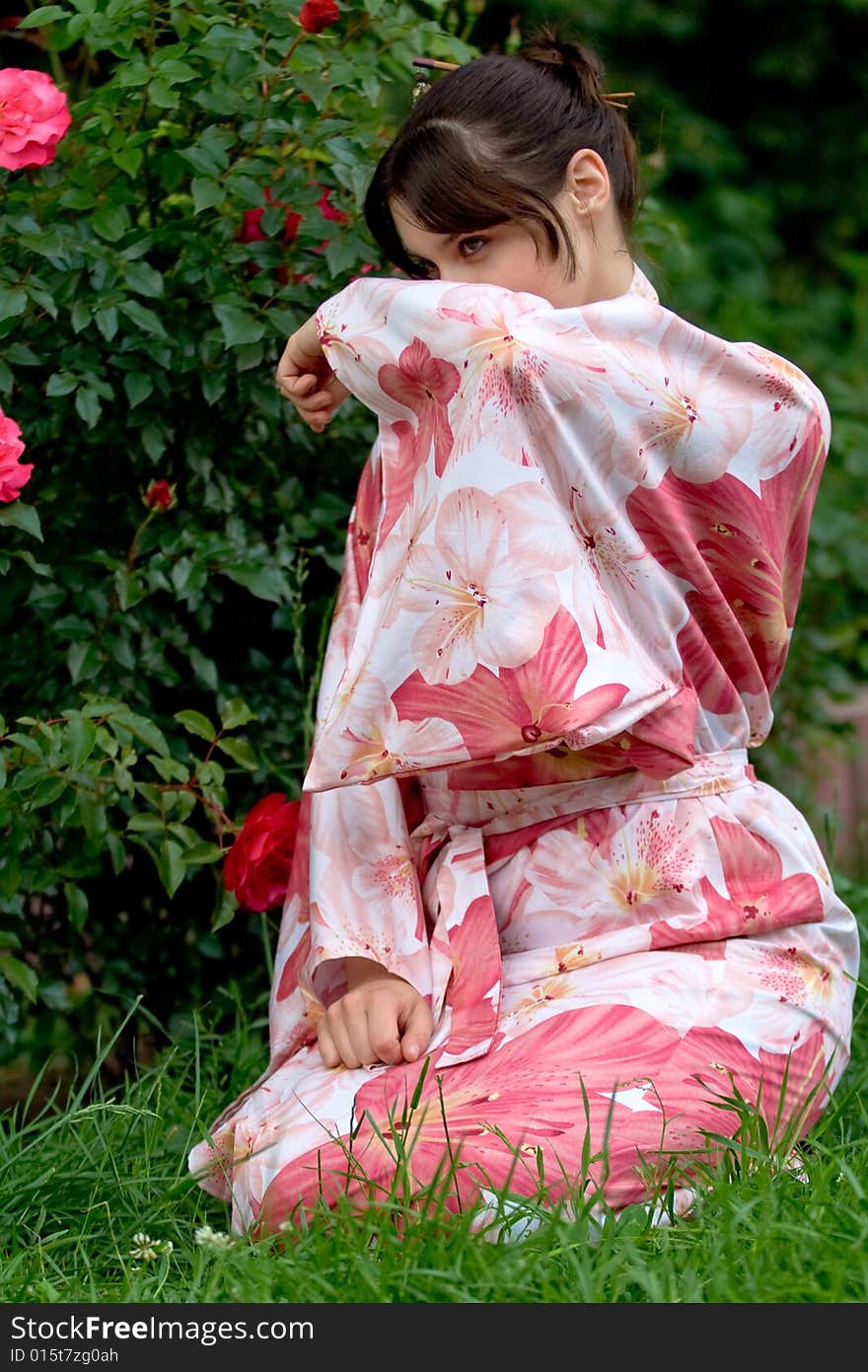 Girl in a pink yukata near rosebush. Girl in a pink yukata near rosebush