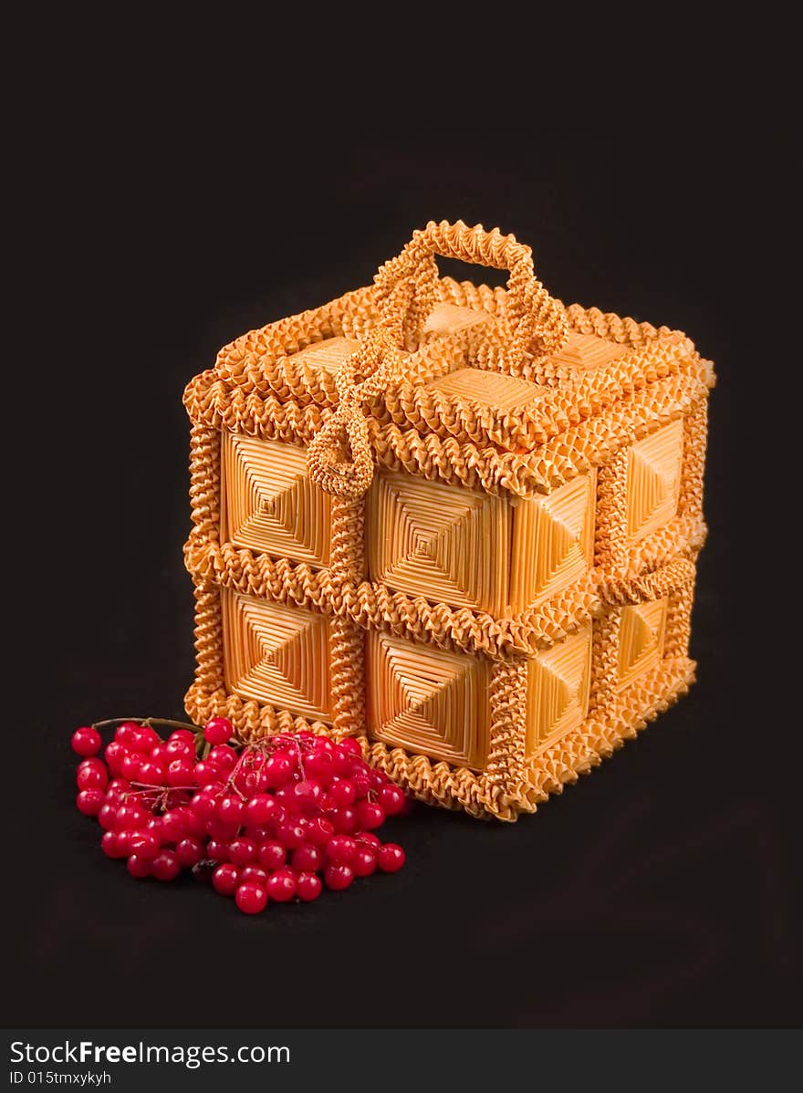 Red berry guelder-rose bush plant and casket from straw on black background