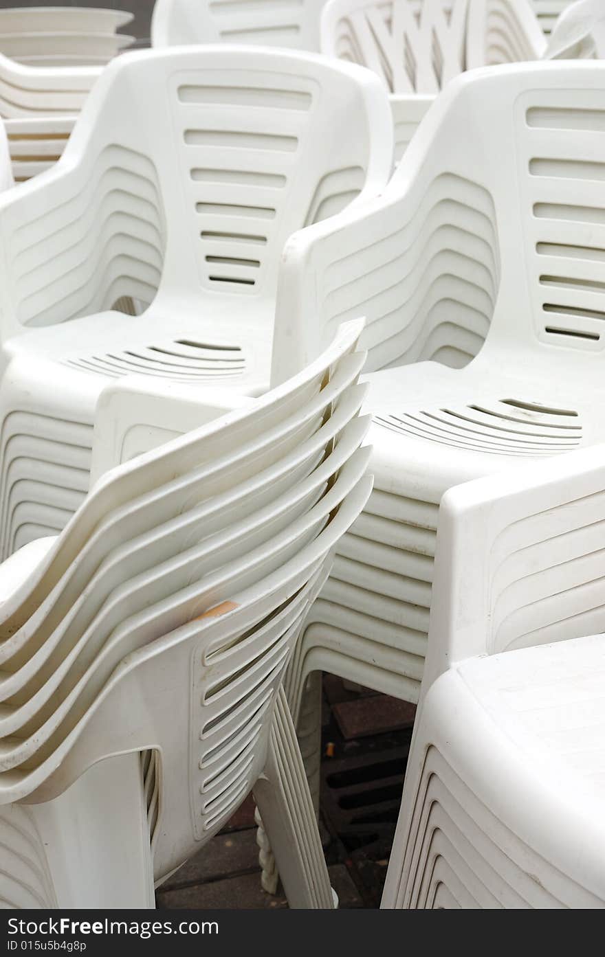 Stack of white plastic chairs on the street