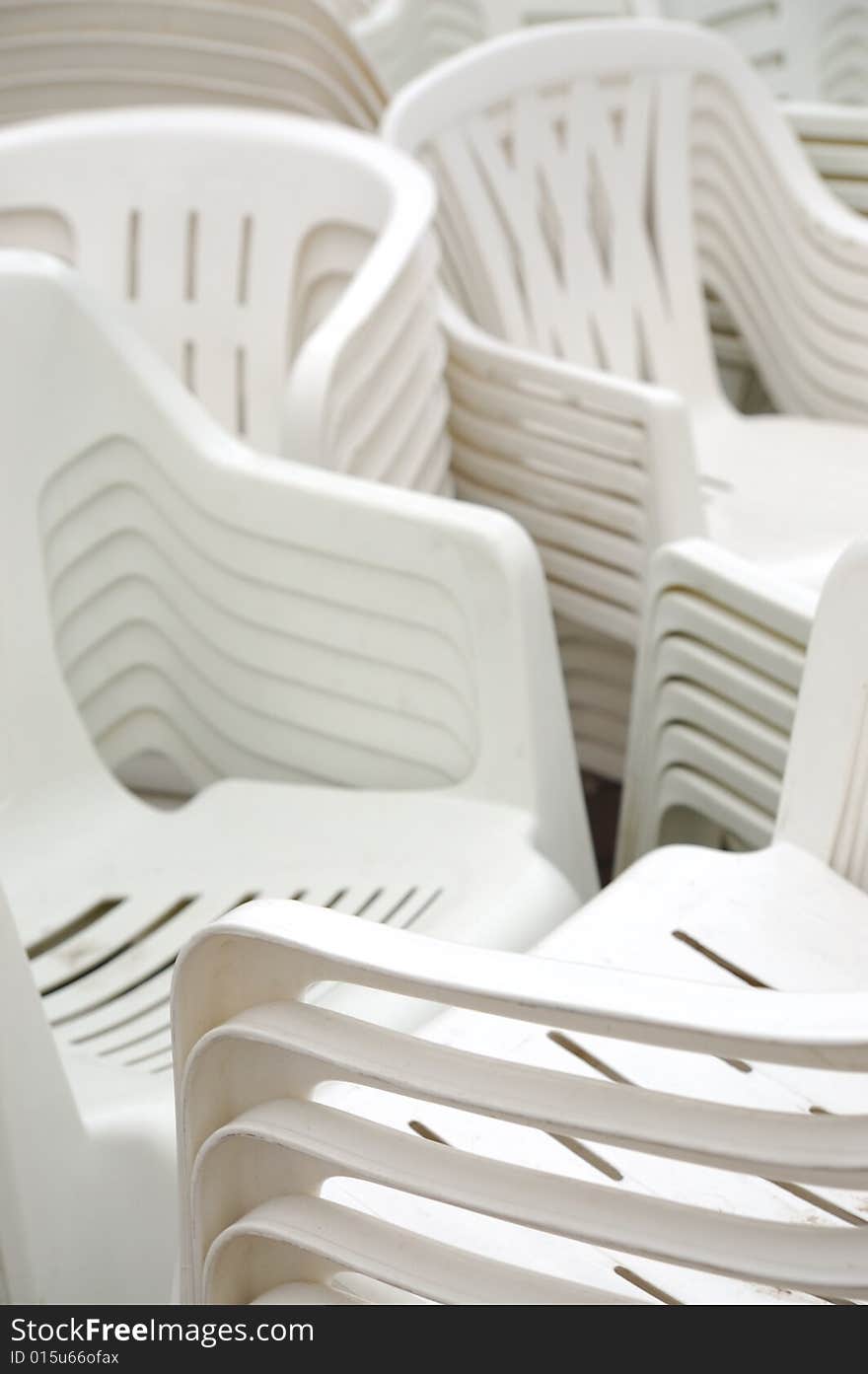 Stack of white plastic chairs on the street