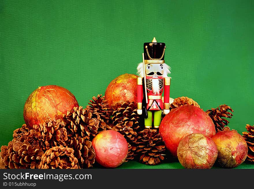 Nutcracker with pnecones and red ball ornaments on rustic green background. Nutcracker with pnecones and red ball ornaments on rustic green background
