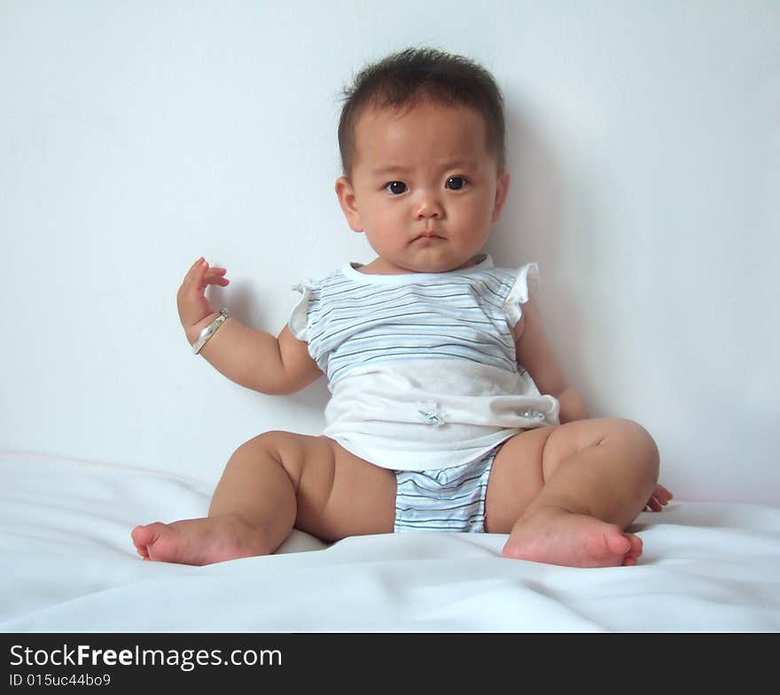 A cute baby is playing on a bed. A cute baby is playing on a bed