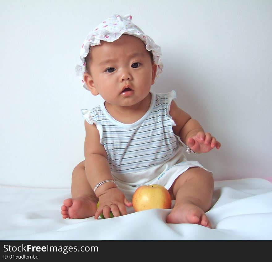 A cute baby with a hat is playing on a bed. A cute baby with a hat is playing on a bed