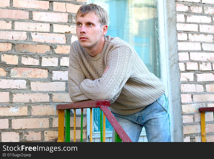 Young Stylish Man Stay On Stairs Near Brick Wall.