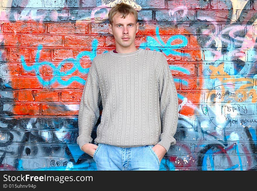 Young stylish man stand near graffiti brick wall.