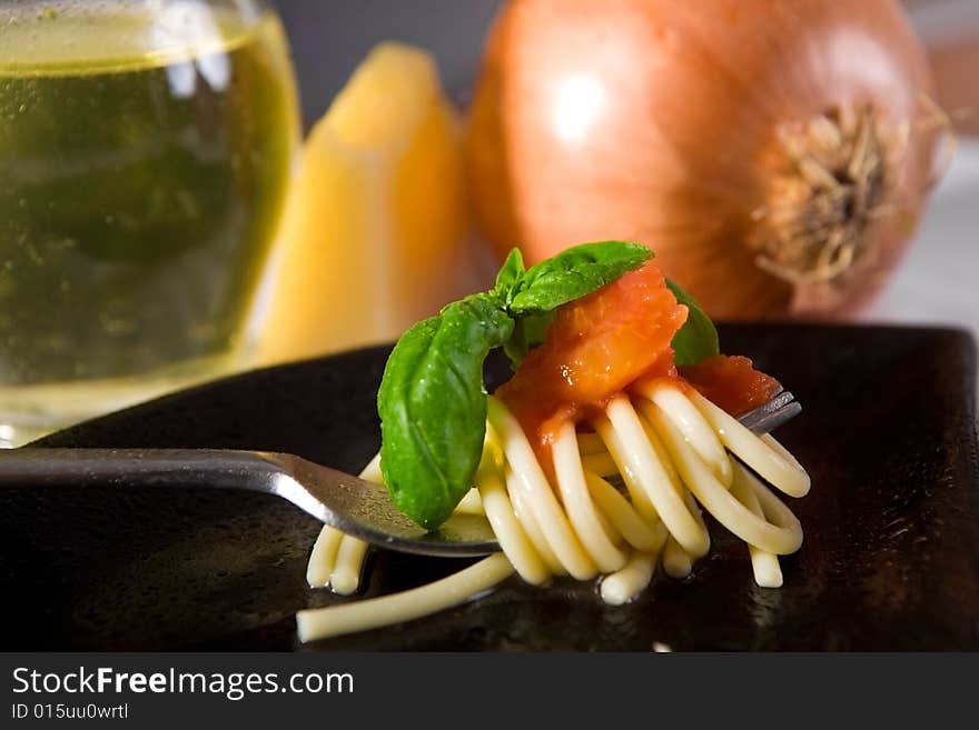 Spaghetti with fresh tomato and basil, with onion, parmesan and olive oil in background