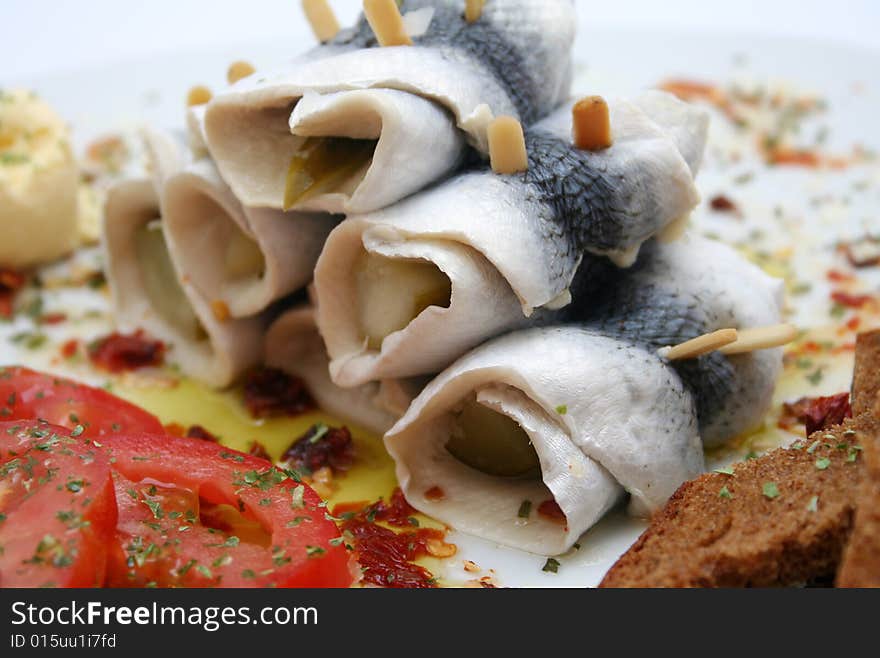 Some fish rolls and tomatoes on a plate. Some fish rolls and tomatoes on a plate