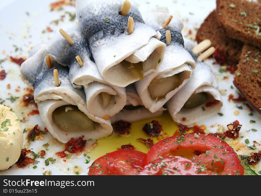 Some fish rolls and tomatoes on a plate. Some fish rolls and tomatoes on a plate