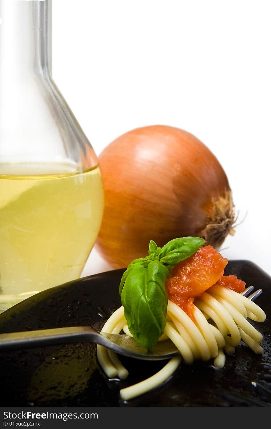 Spaghetti with fresh tomato and basil, with onion and olive oil in background