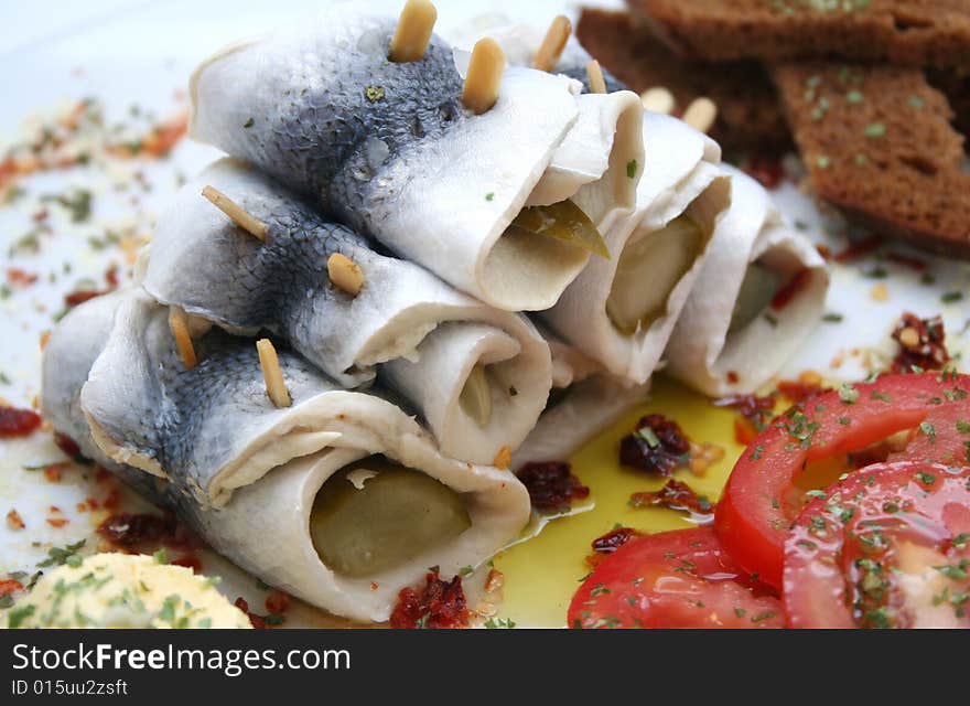 Some fish rolls and tomatoes on a plate. Some fish rolls and tomatoes on a plate