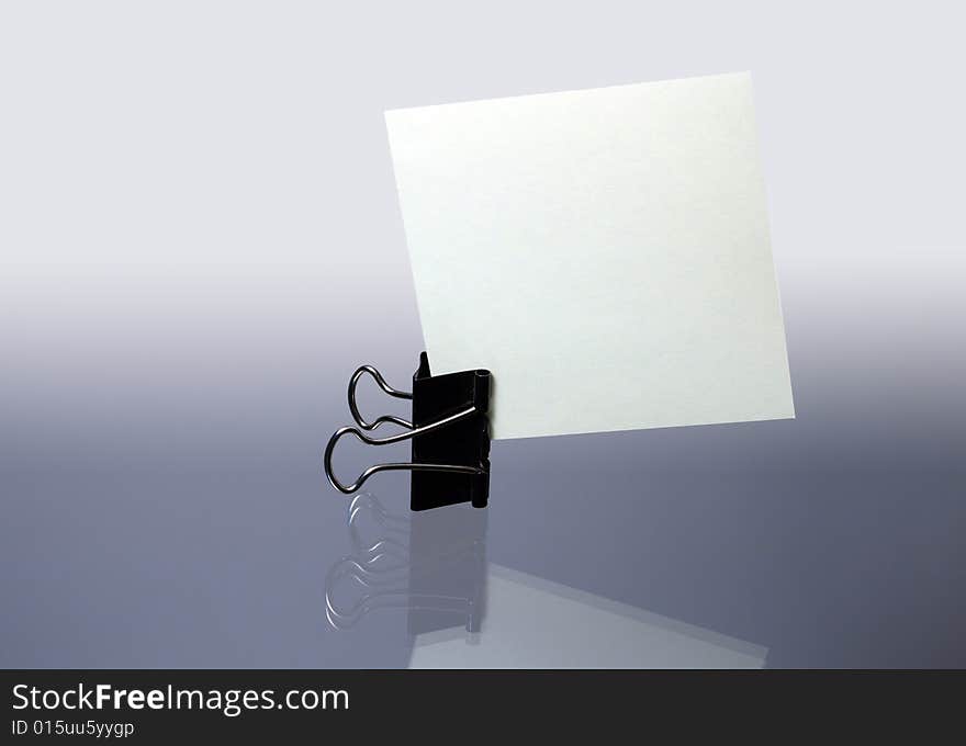 Office fastener with sheet paper standing on gray background. Office fastener with sheet paper standing on gray background