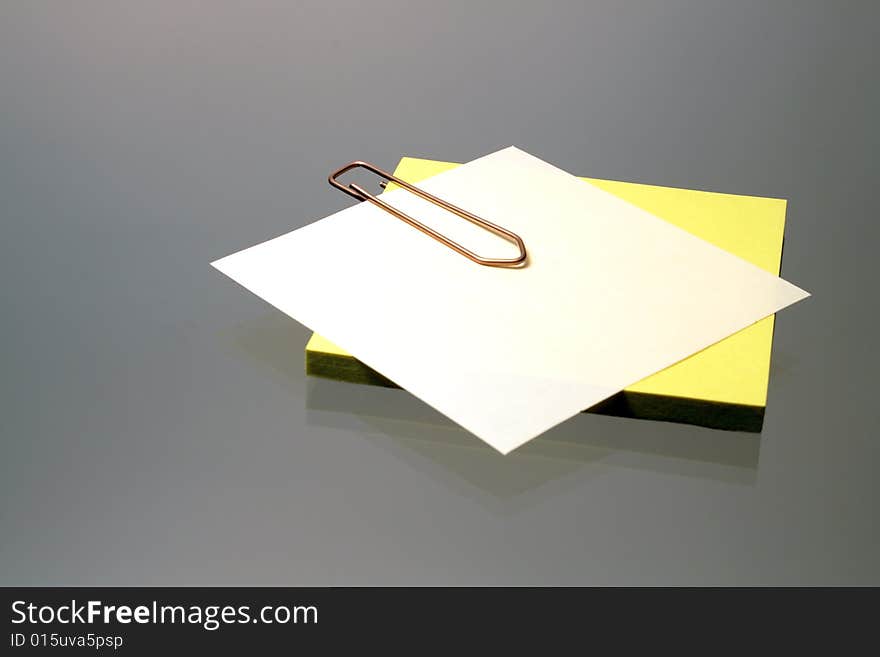 Little sheets of paper fastened with clip on gray background. Little sheets of paper fastened with clip on gray background