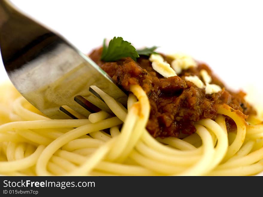 Close up of spaghetti  bolognaise with meat topping with a fork digging in .