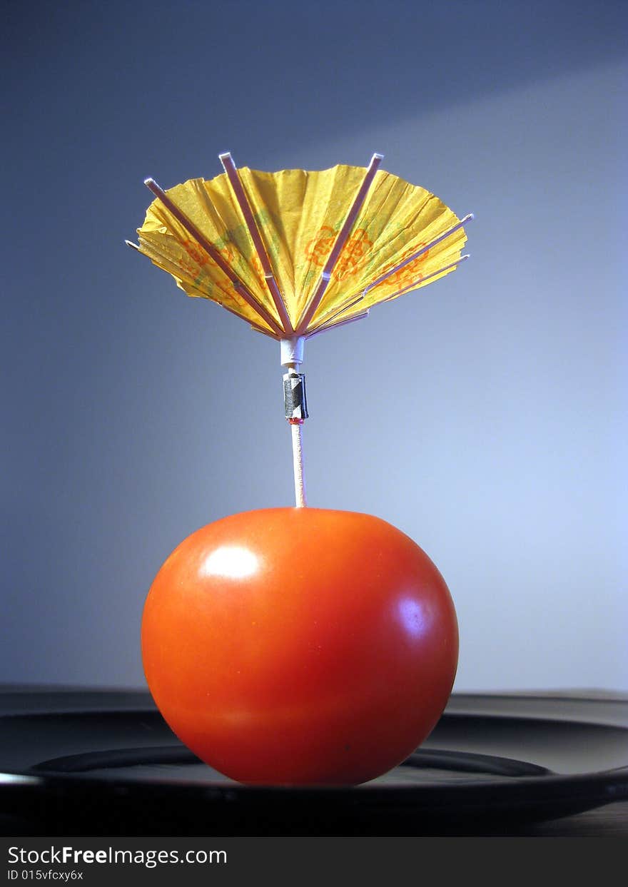 Red tomato with party umbrella metaphor of drink. Red tomato with party umbrella metaphor of drink.