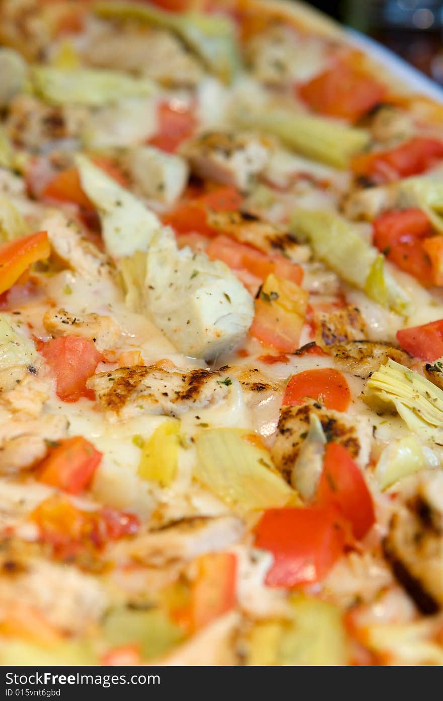 An image of Greek style pizza with artichokes and chicken