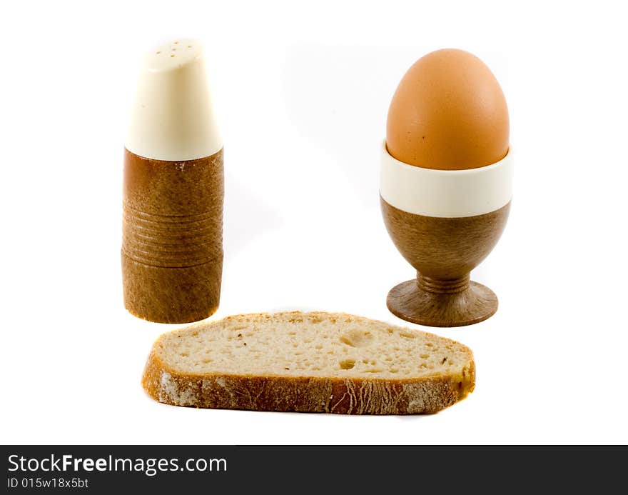 A soft boiled egg, a slice of bread and a saltpot