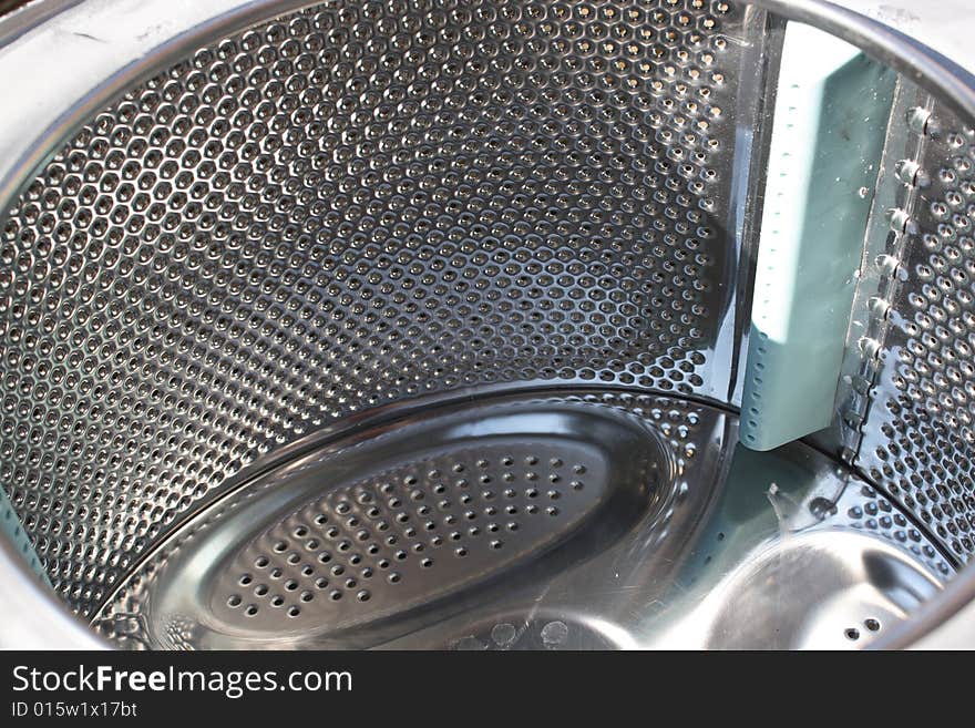 The inside of a shiny washing machine stainless steel drum. The inside of a shiny washing machine stainless steel drum