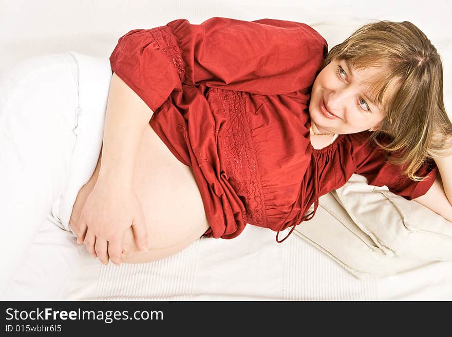 A pregnant lady with a red shirt touching her stomach. A pregnant lady with a red shirt touching her stomach