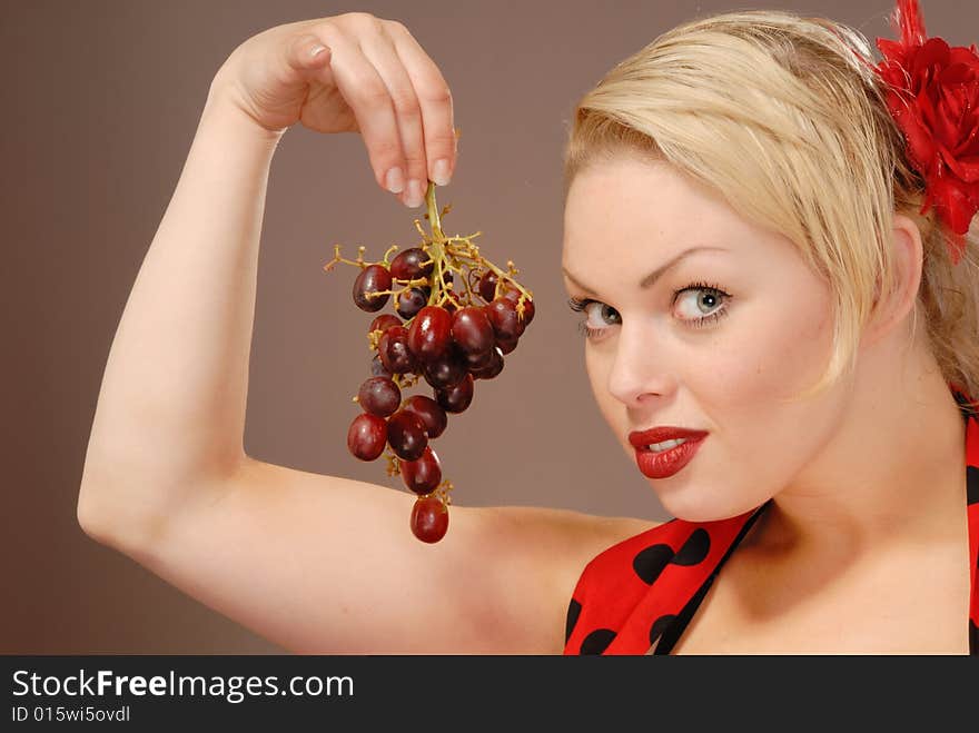 Pretty girl holding red grapes to tempt you. Pretty girl holding red grapes to tempt you