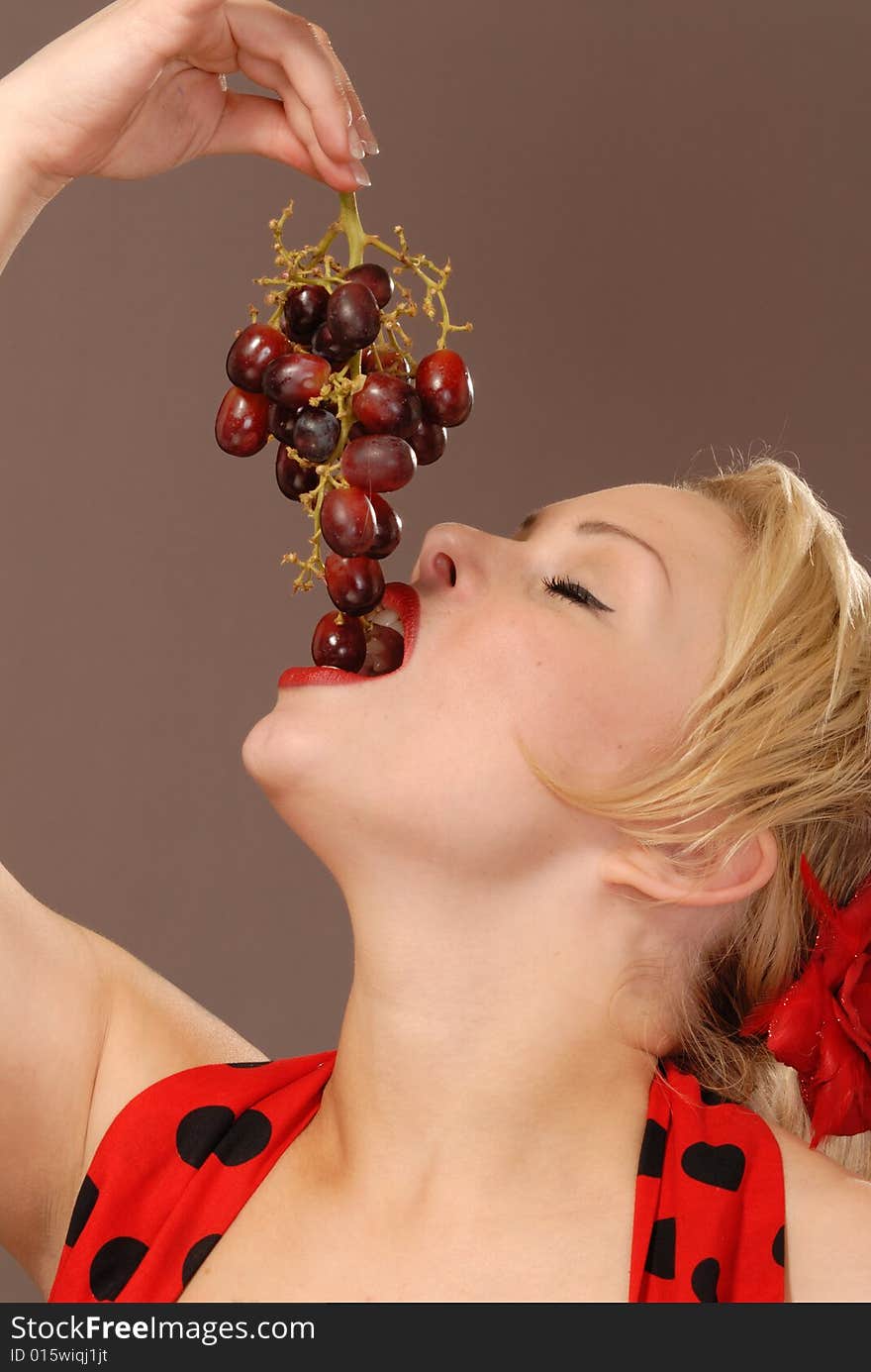 Pretty girl holding up red grapes and tasting them. Pretty girl holding up red grapes and tasting them