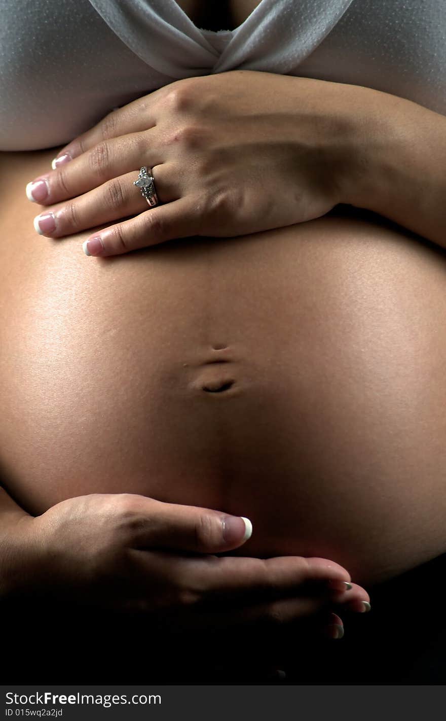 Young expectant mother sitting, holding her abdomen. Young expectant mother sitting, holding her abdomen