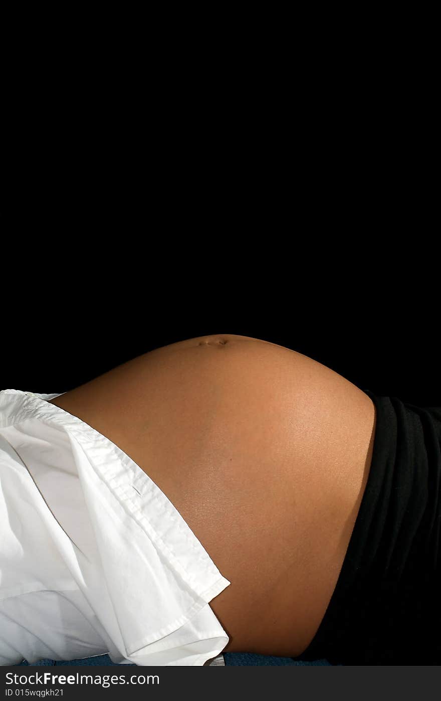 Young mother reclining in front of a black background. Young mother reclining in front of a black background