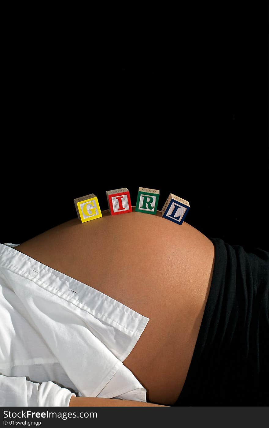 Young mother reclining in front of a black background with GIRL spelled out with child's toy blocks. Young mother reclining in front of a black background with GIRL spelled out with child's toy blocks