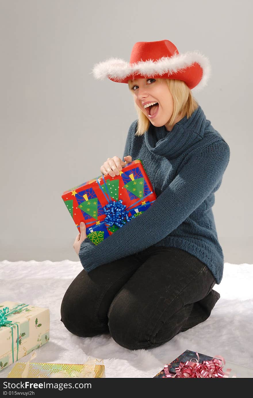 Excited cute blond girl wearing red hat holds Xmas gift. Excited cute blond girl wearing red hat holds Xmas gift